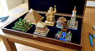 Prompt: "The box contains exquisite 3D Perler bead figurines representing the Seven Wonders of the Ancient World."'