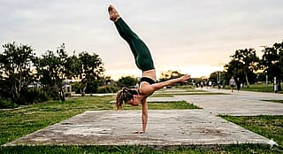 Woman doing one-arm handstand'